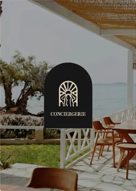 Enseigne Meraki « Conciergerie » sur une terrasse face à la mer.